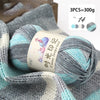 A close-up of gray and turquoise gradient acrylic yarn skeins used for knitting or crochet projects.