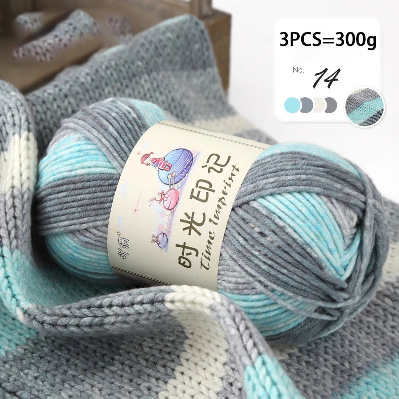 A close-up of gray and turquoise gradient acrylic yarn skeins used for knitting or crochet projects.