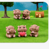 Three cute mini hippo resin figurines in pink and brown sitting on green grass.