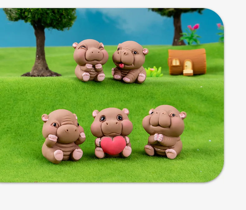 Three cute mini hippo resin figurines in pink and brown sitting on green grass.