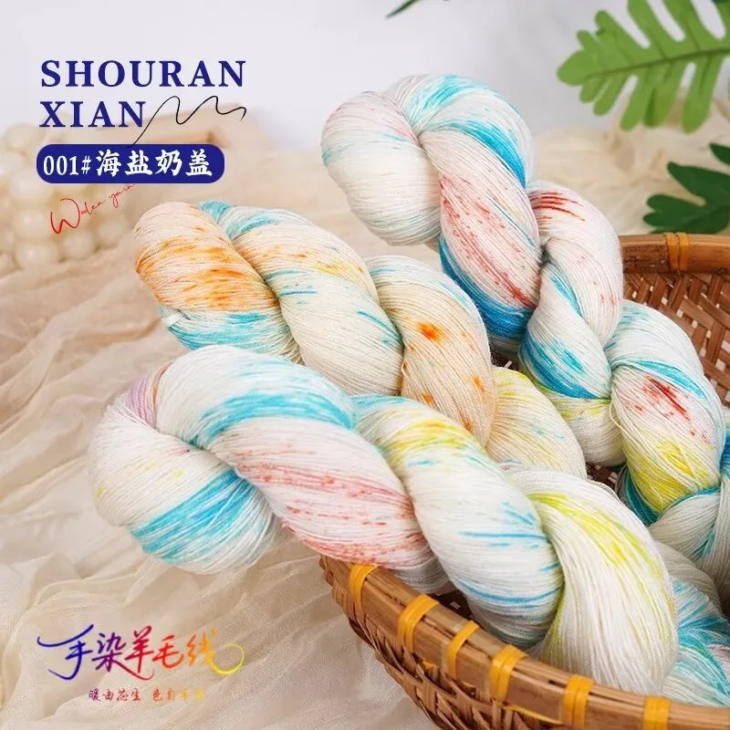 A bundle of hand-dyed Australian wool yarn in a gradient of white, pink, and blue is shown in a woven basket.