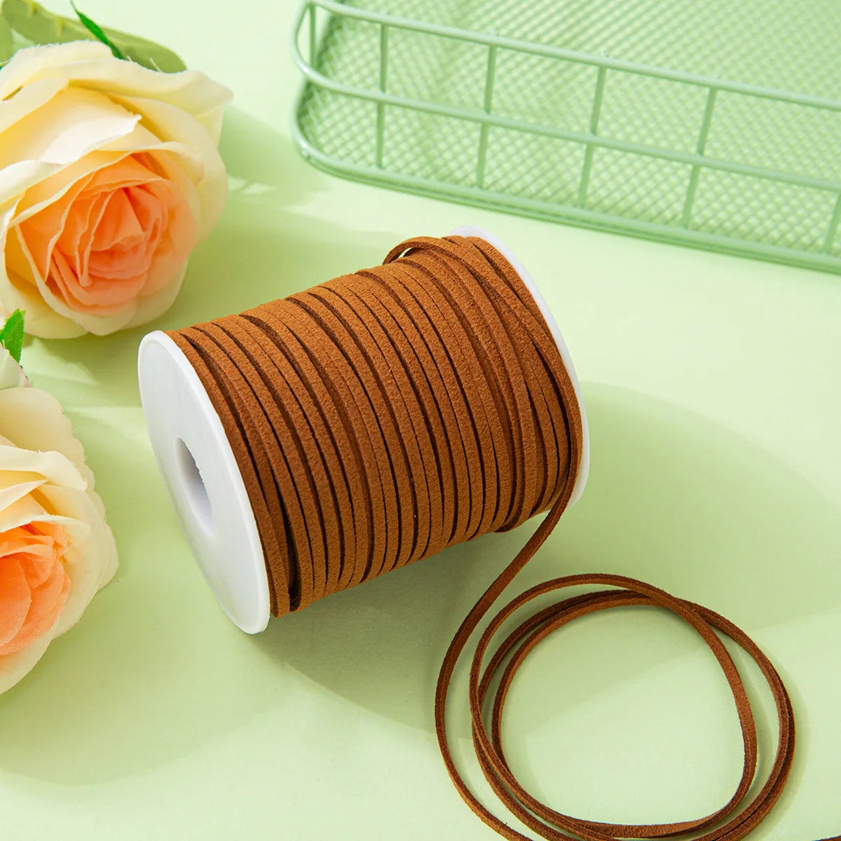 A roll of brown velvet faux suede braided ribbon for crafting and gift wrapping, resting on a light green surface.