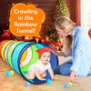 A baby is crawling through a colorful rainbow tunnel play structure indoors.