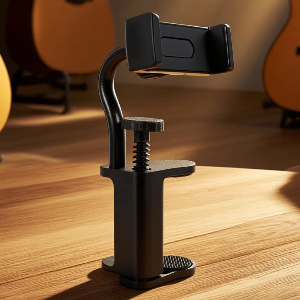 A black hands-free guitar phone holder with an adjustable clamp resting on a wooden surface.