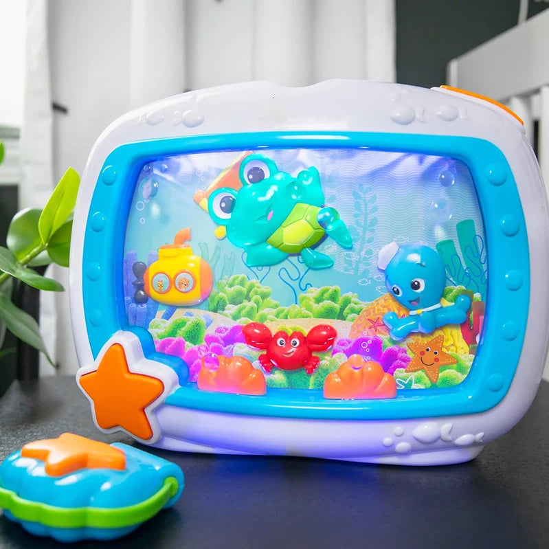 A white and blue ocean-themed crib soother with a clear window featuring colorful sea creatures.
