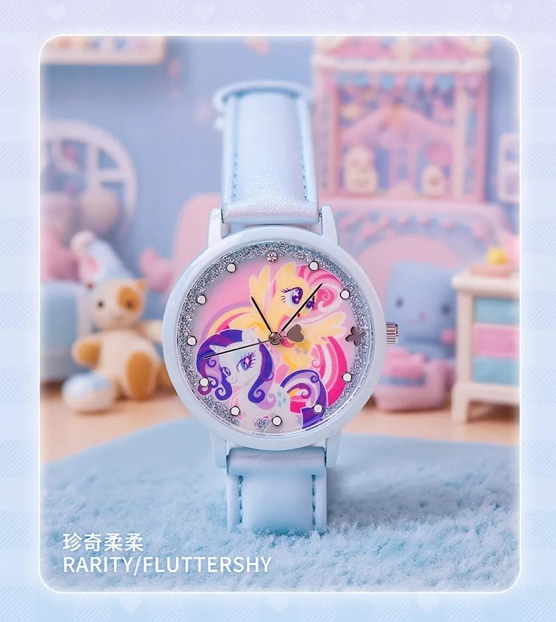 A light blue watch with a pink and purple enamel face featuring a unicorn design, set against a soft background.