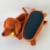 An orange dachshund plush slipper with a black interior lining is shown lying on a white surface.