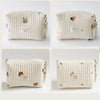 A cream quilted baby diaper caddy organizer with small animal embroidery and attached stroller straps.