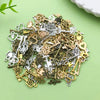 A pile of vintage brass and silver key charms for jewelry making scattered on a light green surface.