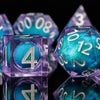 A collection of iridescent purple and blue resin dice, including a d4, d6, and d8, are displayed on a dark surface.