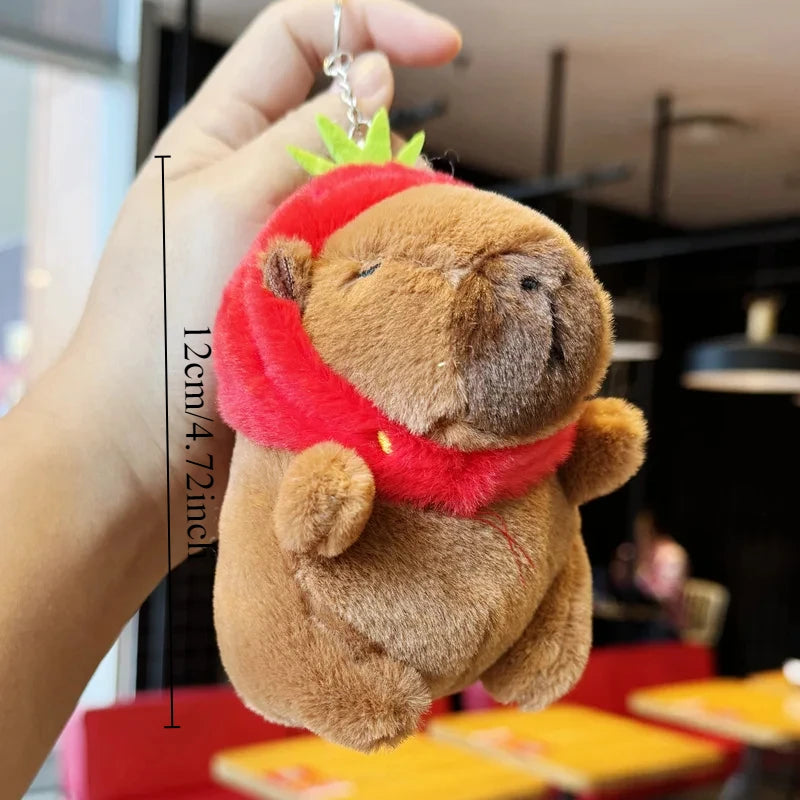 A brown capybara plush toy with a red scarf and four smaller baby capybaras.
