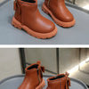A pair of tan faux leather winter boots with suede lining and stitching displayed on a gray surface.