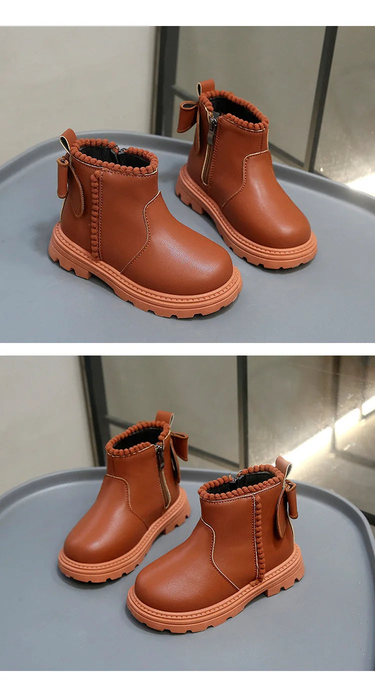 A pair of tan faux leather winter boots with suede lining and stitching displayed on a gray surface.