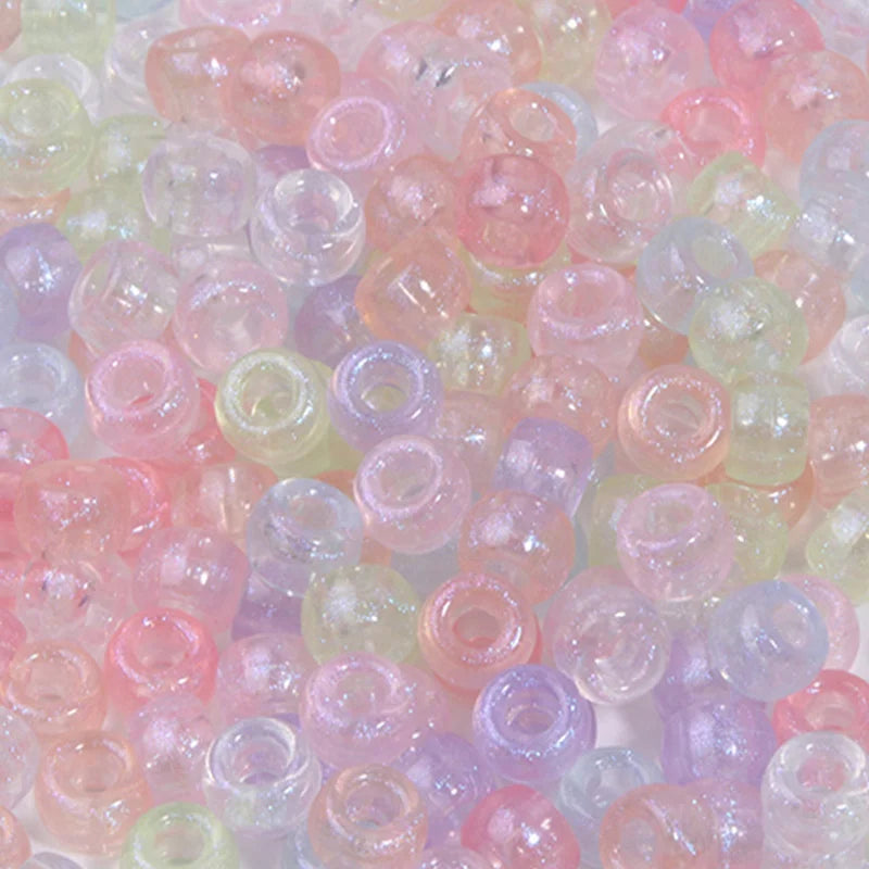 A close-up view of a 100-pack of iridescent rainbow pony beads in various shades of pink, purple, and green.