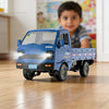 A blue 1:16 scale RC truck with a truck bed and wheels is shown on a wooden floor.