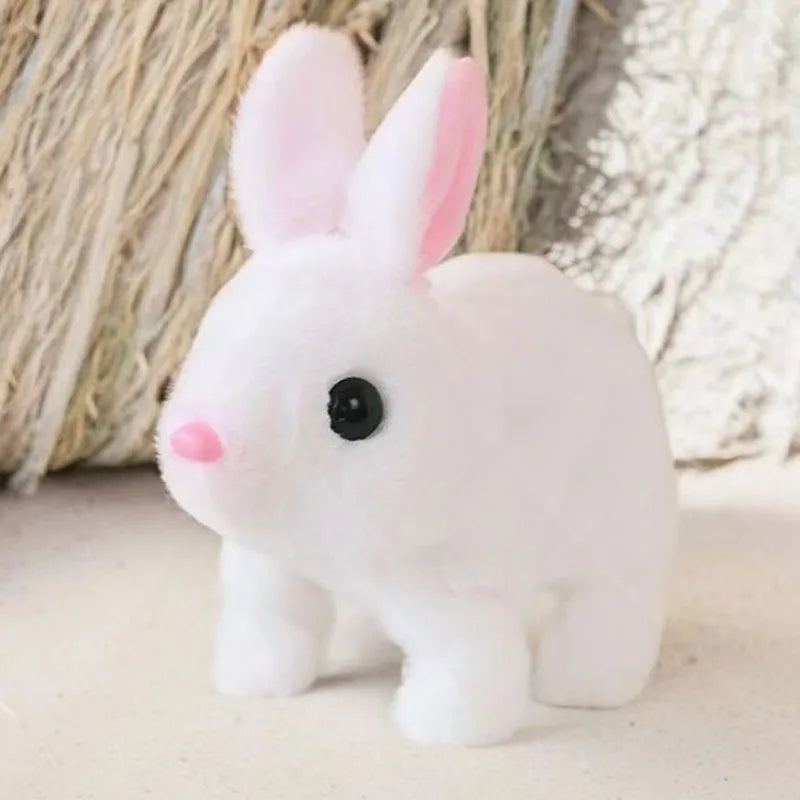 A white electric plush rabbit toy with pink inner ears sitting on a light surface.