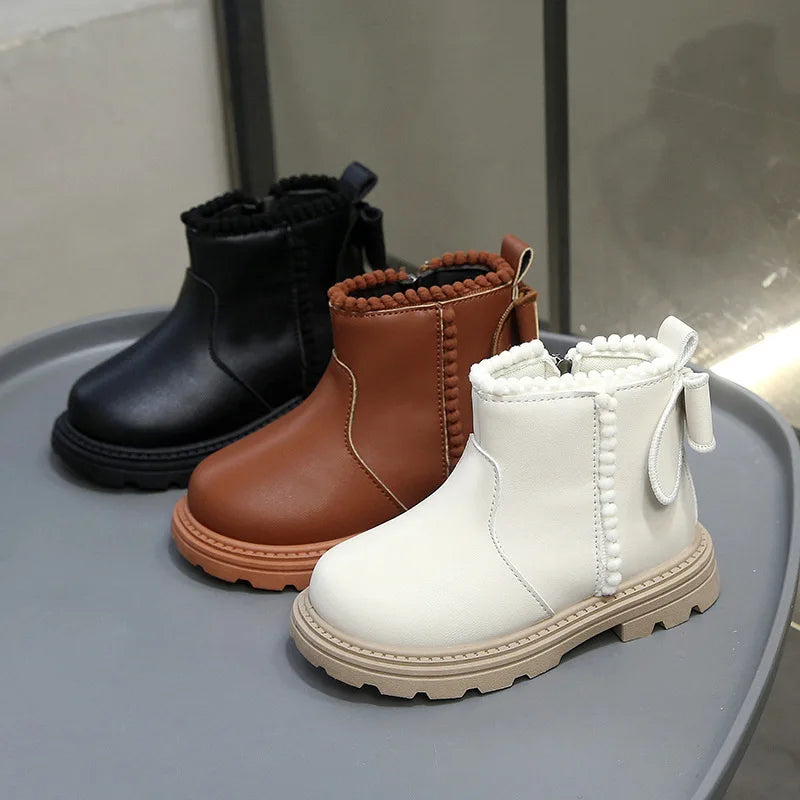 A display of three winter boots in black, brown, and cream faux leather finishes.