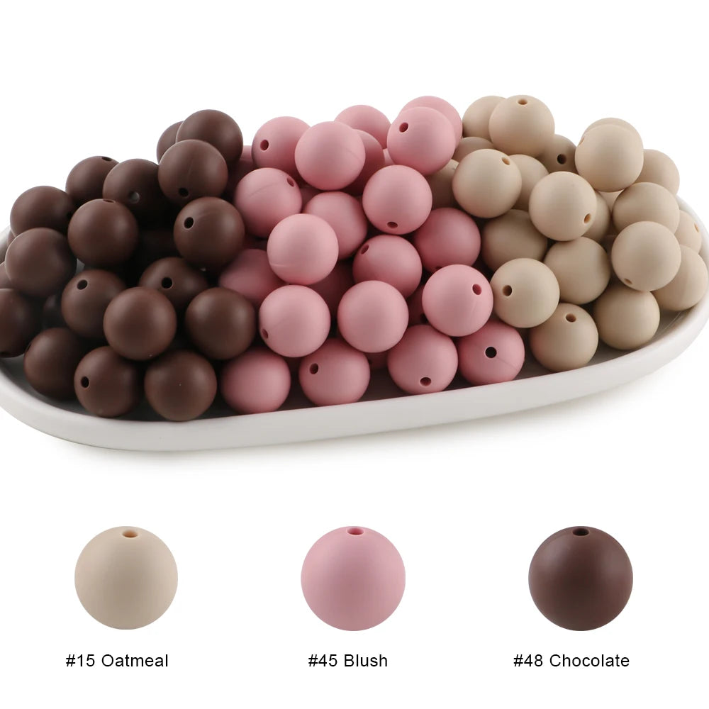 A collection of round silicone beads in various shades including oatmeal, blush pink, and chocolate brown.