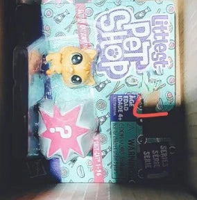 A close-up photo of a packaged set of mini posable animal figures featuring a yellow creature and various accessories.