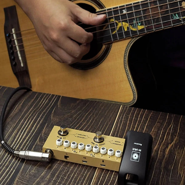 A close-up shot of a yellow multi-effects guitar and bass pedal resting on a wooden surface next to a guitar neck.