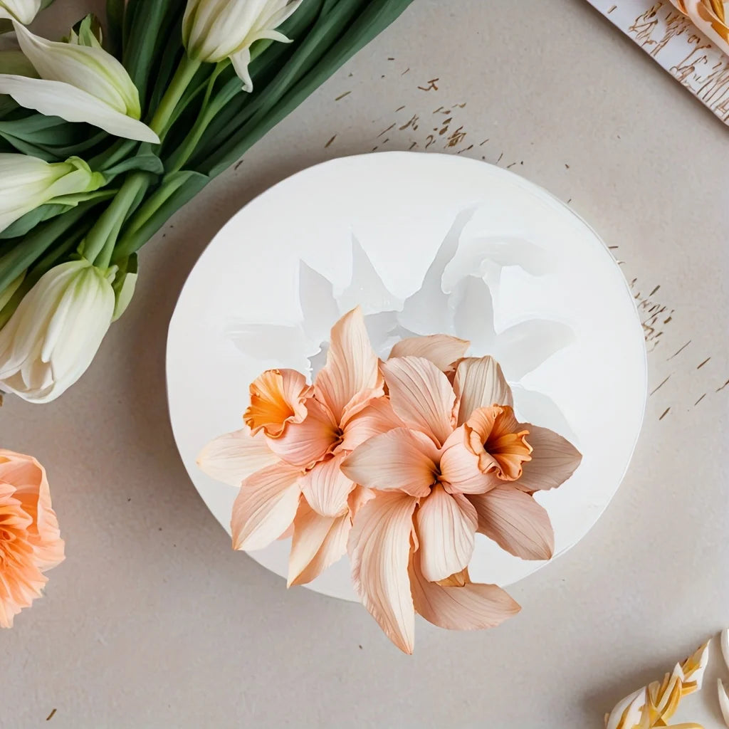 A light peach floral silicone mold rests on a neutral surface next to white tulips.