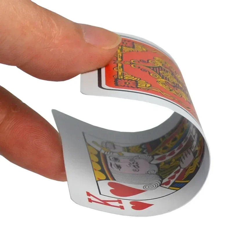 A hand holds a deck of waterproof plastic playing cards with decorative designs.