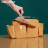 A hand is opening a tan leather stroller cup and bottle holder, showing the interior compartments.
