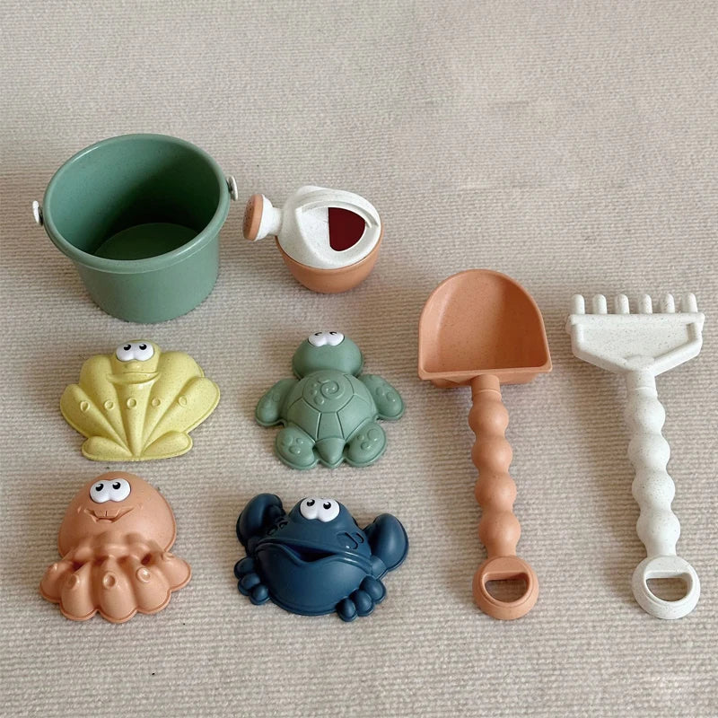 A set of kids sand and water play items including a green bucket, an orange bulldozer, and various plastic toys.