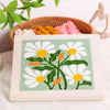 A punch needle embroidery kit featuring a white and yellow daisy flower pattern on a light green fabric.