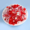 A mix of red and pink acrylic beads for DIY jewelry making, including various shapes like hearts and teardrops.