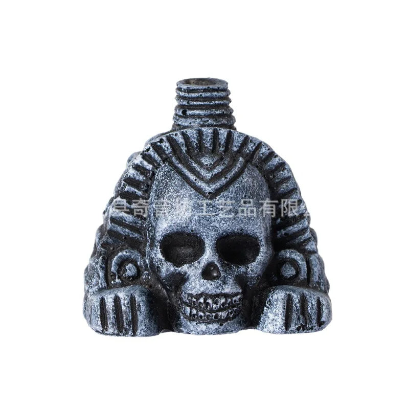 A dark gray stone carving of an Aztec death whistle skull with intricate patterns.