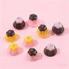 A collection of pudding-shaped resin pendants in pink and brown colors arranged on a light pink background.