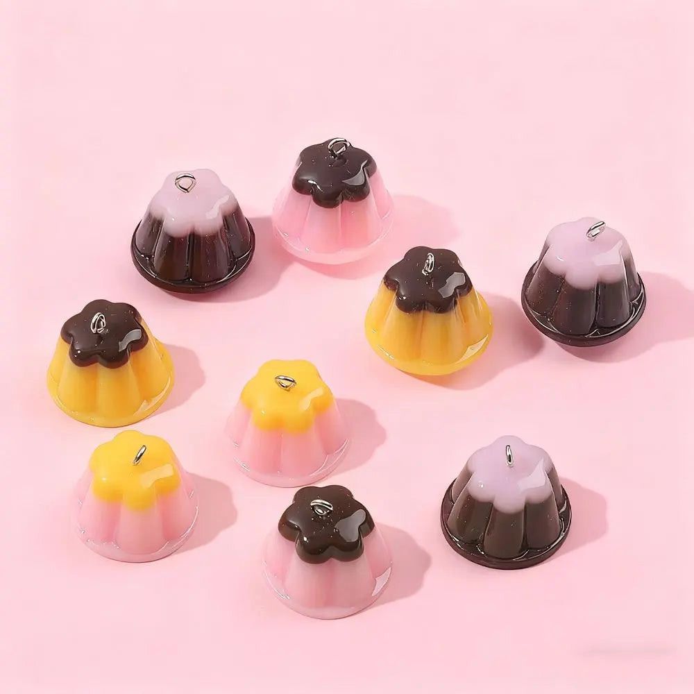 A collection of pudding-shaped resin pendants in pink and brown colors arranged on a light pink background.