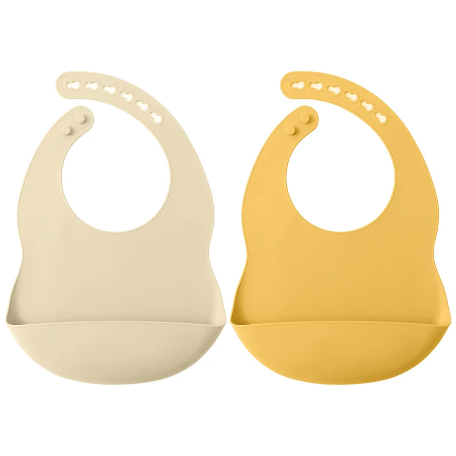 A pair of light beige and yellow waterproof silicone baby bibs with adjustable necks.