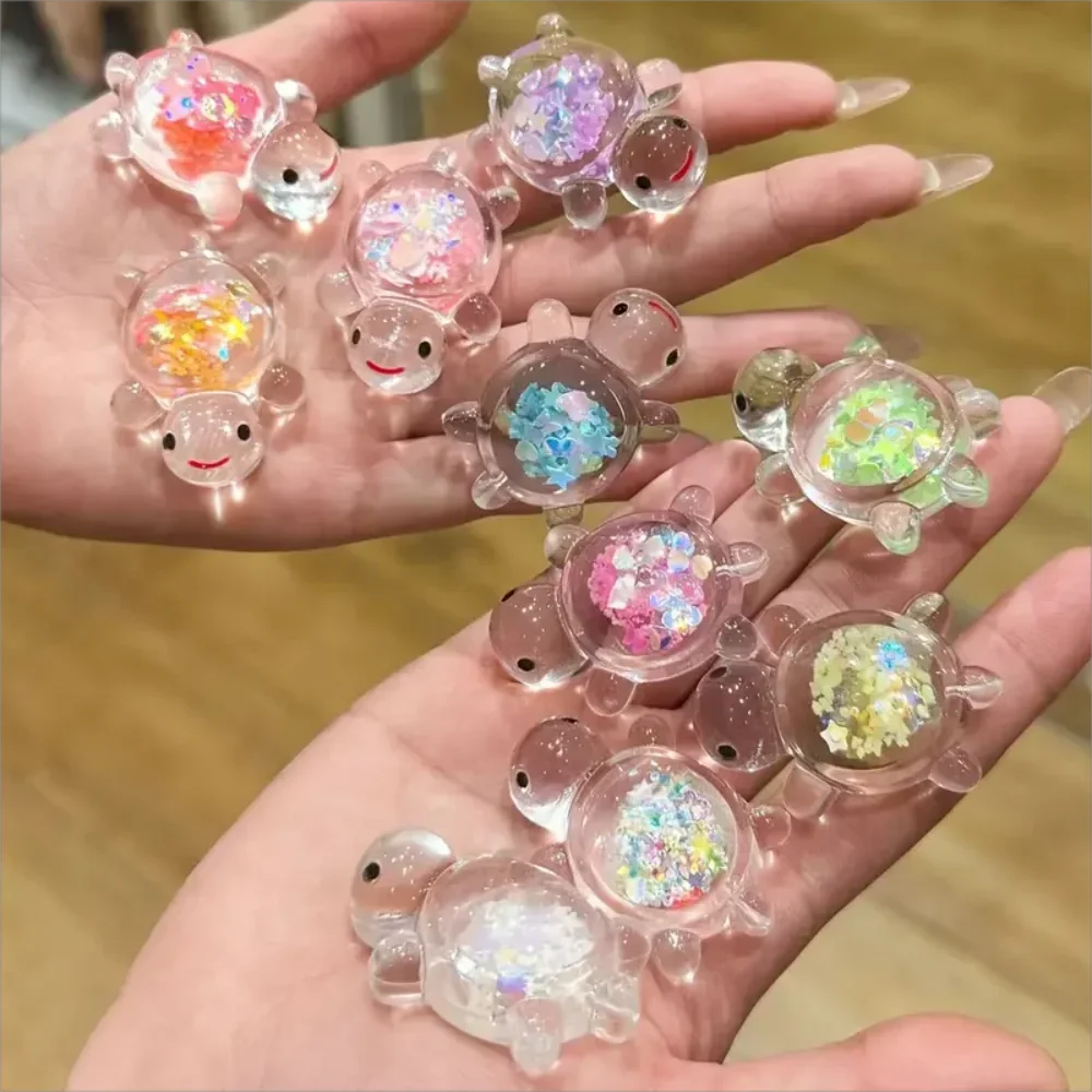 A hand holds several glow-in-the-dark mini sea turtle figurines for craft projects.