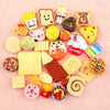 Assorted candy resin flatbacks for DIY crafts and jewelry making arranged on a pink background.
