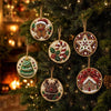 A close-up of various handmade Christmas diamond painting ornaments hanging on a green fir tree.