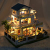 A detailed diorama of a DIY wooden mini seaside villa dollhouse kit featuring furniture and exterior landscaping.
