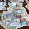 A collection of vintage washi paper sticker sheets in various grid and striped patterns scattered on a light-colored surface.