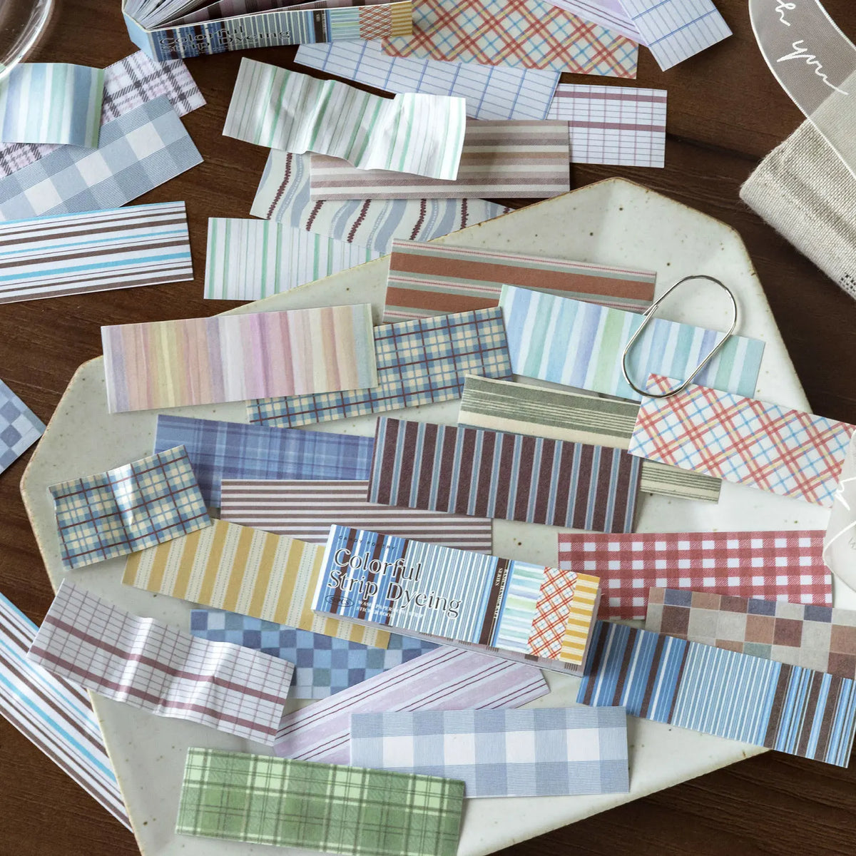 A collection of vintage washi paper sticker sheets in various grid and striped patterns scattered on a light-colored surface.