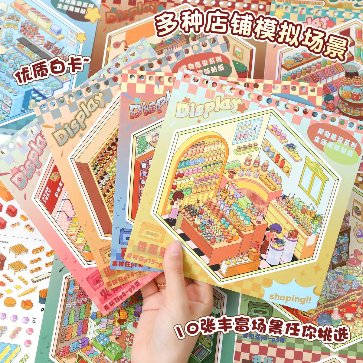 A hand holds a colorful sticker book featuring various shop displays and scenes for DIY crafts.
