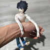 A hand is holding a poseable L Lawliet plush doll with black hair and white clothing.