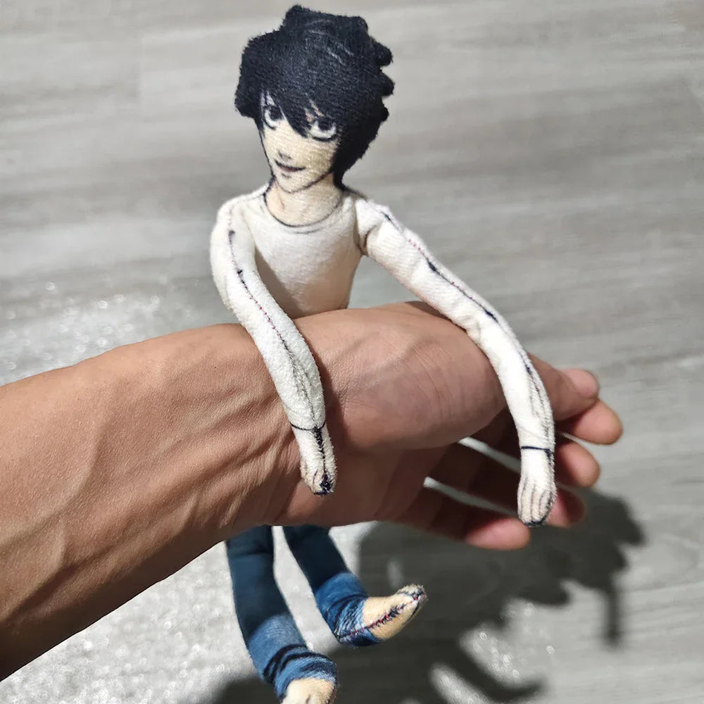 A hand is holding a poseable L Lawliet plush doll with black hair and white clothing.