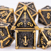 A close-up of a gold and black metal dice set featuring skull and dragon designs for tabletop role-playing games.
