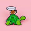 A green turtle enamel pin with a speech bubble saying Weeeeeee!