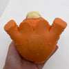 An orange squishy stress ball shaped like a Highland cow head with a yellow tuft, held in a hand.
