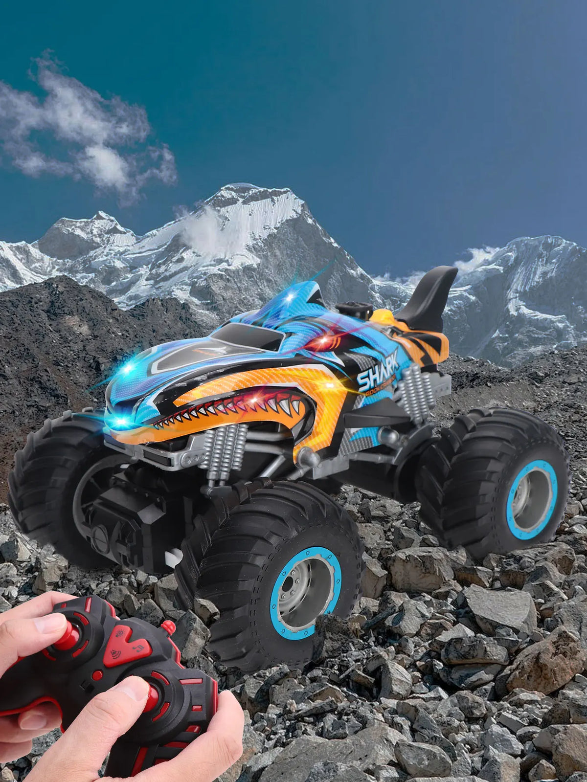 An orange and blue All-Terrain RC Monster Truck is shown in a rugged, rocky outdoor environment.