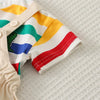 A close-up of a kids' striped dinosaur two-piece outfit set featuring yellow, green, and blue stripes on a light fabric.