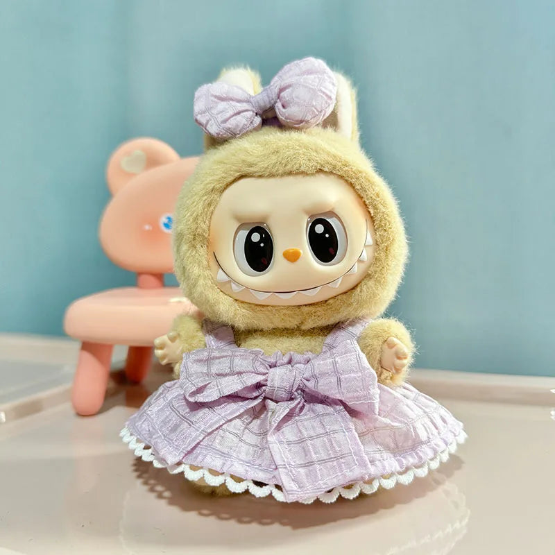 A cute yellow doll wearing a lavender plaid dress and bow, standing next to a pink chair.