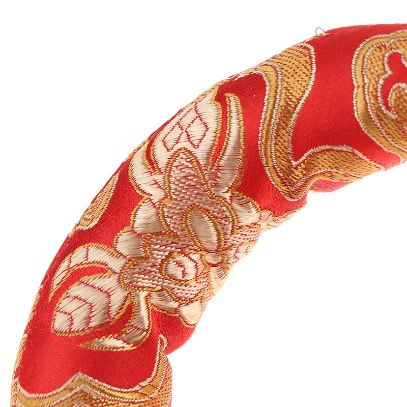 Close-up of a red fabric featuring intricate gold embroidery and decorative patterns.